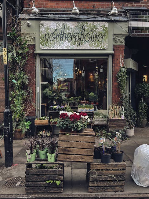 The exterior of Northern Flower, a florist on Malden high street, featuring a brick building with a light green sign displaying the shop's name. In front of the shop, there are wooden crates filled wi