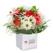 Radiating with the cheerful energy unique to Motspur Park, this sumptuous bouquet is artfully composed inside a square white gift bag, its pure lines drawing the eye to each thoughtfully selected bloom. Lush coral and spirited red carnations appear almost to flutter, their ruffled edges creating a symphony of colour and texture reminiscent of wildflowers skirting the playing fields off Claremont Avenue. Bright white daisies, crowned with zesty green-yellow centers, add a playful touch while soft clouds of baby's breath meander between them, infusing the whole arrangement with a sense of gentle whimsy and innocent delight. Hints of purple-tipped buds peek out on the left, inviting discovery in the same way the community welcomes new faces. The base of the bouquet is circled by glossy, emerald green leaves, forming a cradle of support both sturdy and graceful. Presented with elegant white ribbon handles against a seamless white backdrop, this arrangement is ready to uplift any occasion-birthdays, thank-yous, or just-because gestures-by bringing a little of Motspur Park's neighbourly heart and vibrant character to someone's day through local, reliable delivery.